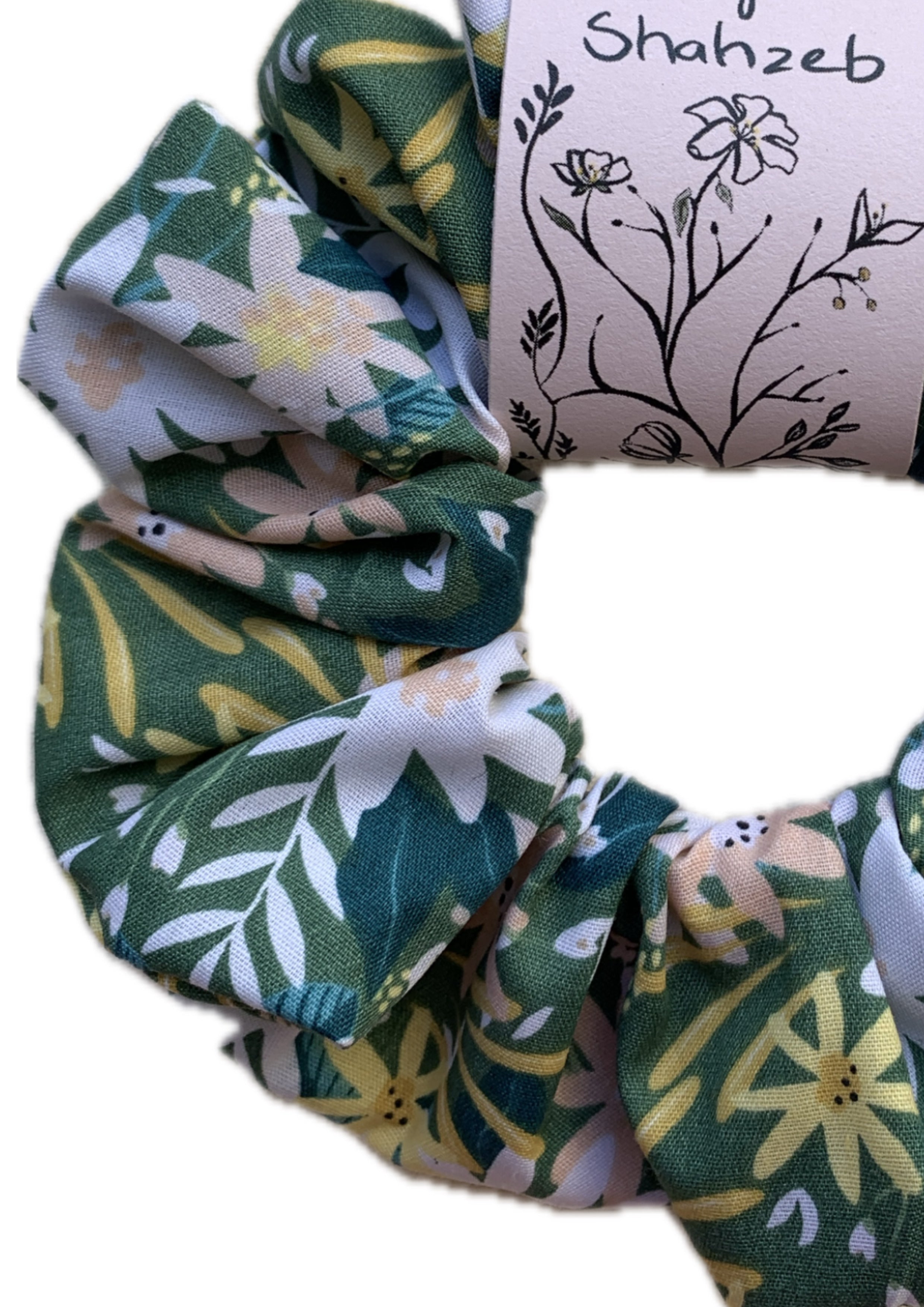A fabric hair scrunchie with a green, white, and yellow floral pattern.