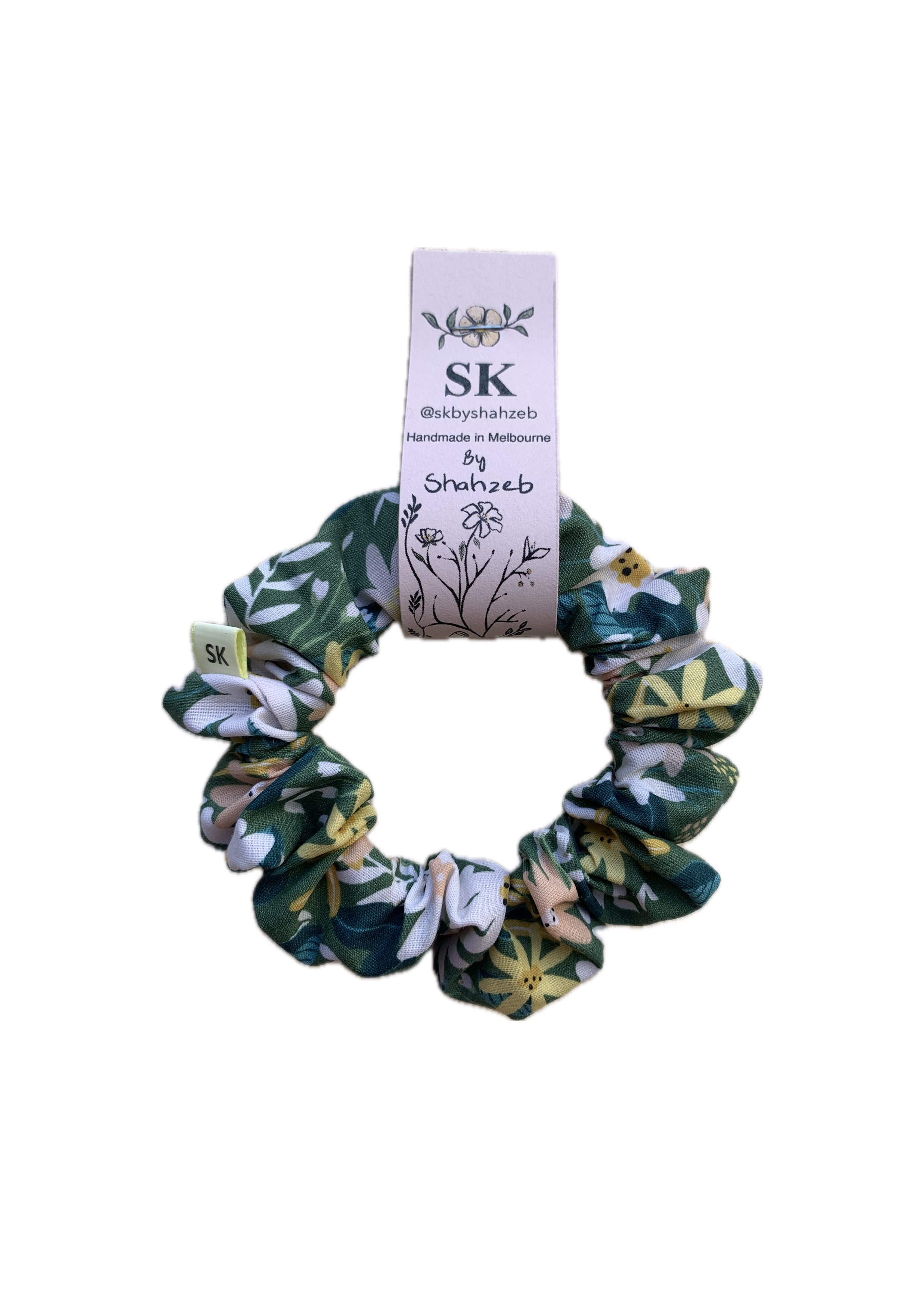 A fabric scrunchie with a green, white, and yellow floral pattern.