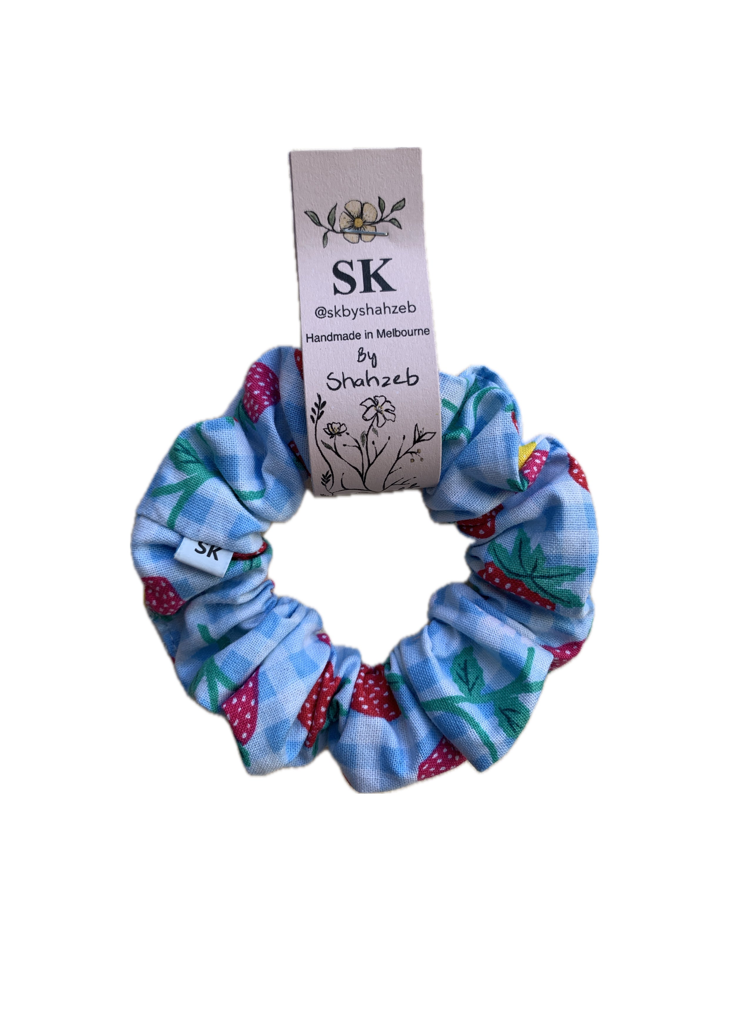 A fabric scrunchie with a strawberry and blue gingham pattern.