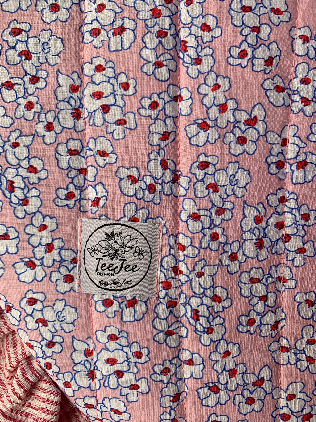 Pink cotton fabric with a white and red floral print.