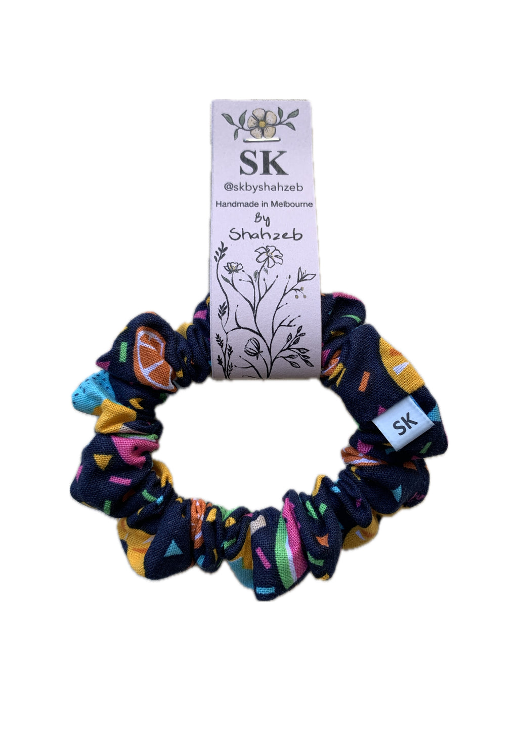 A multicolor scrunchie with a navy blue base and a colorful geometric fruity print,