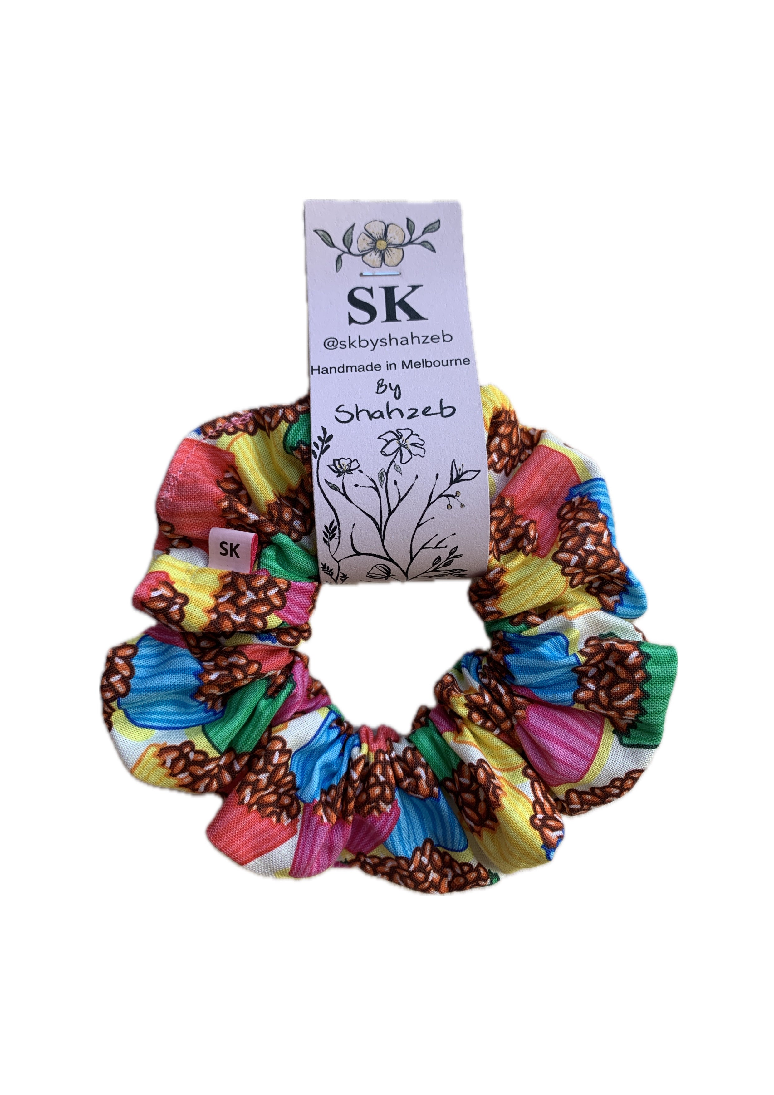 A multicolor fabric scrunchie with cupcake print in pink, yellow, blue, green, and brown.