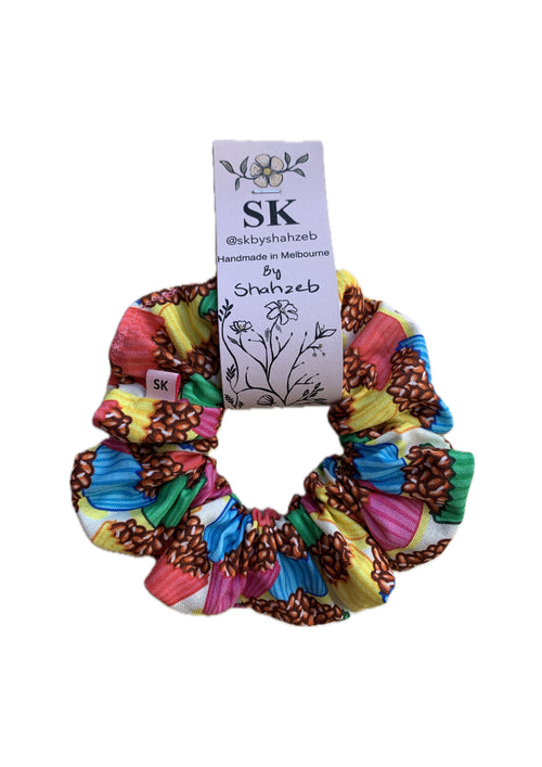 A multicolor fabric scrunchie with cupcake print in pink, yellow, blue, green, and brown.