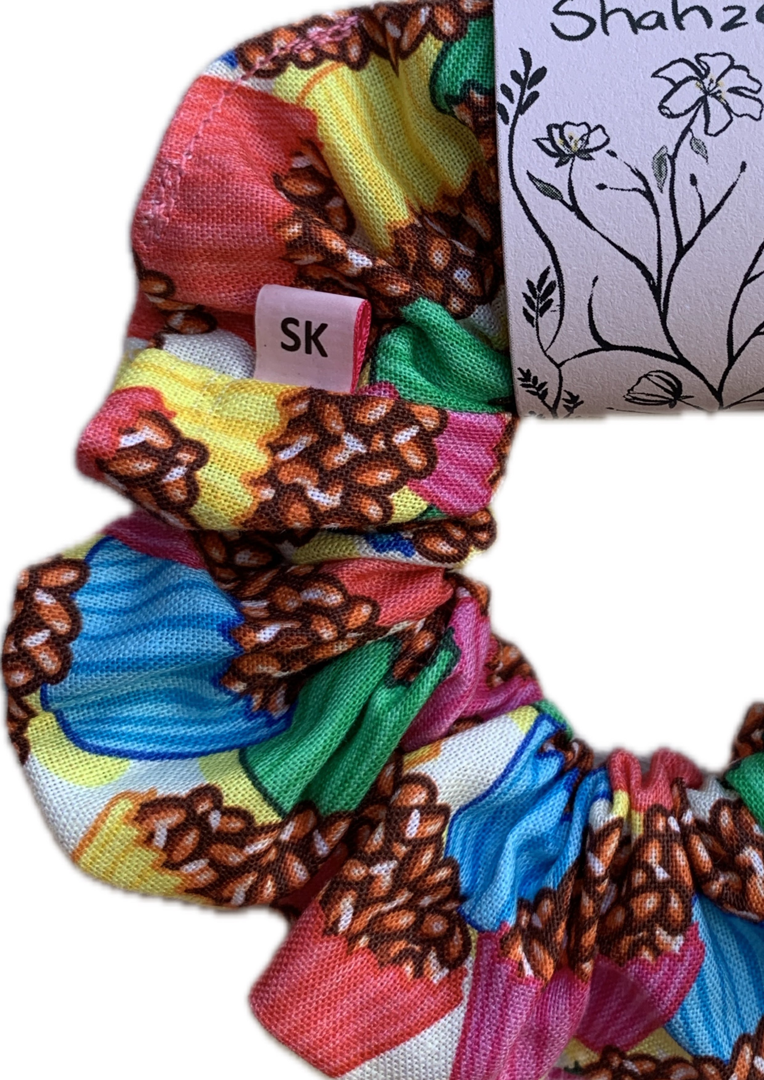 A colorful fabric scrunchie with a brown coffee bean pattern over a multicolor background of red, yellow, green, blue, and pink. 