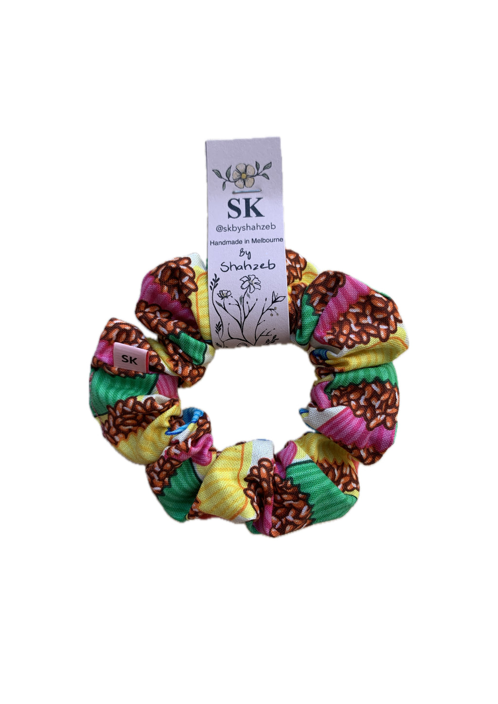 A multicolor fabric hair scrunchie with a cupcake pattern of brown, pink, yellow, and green.