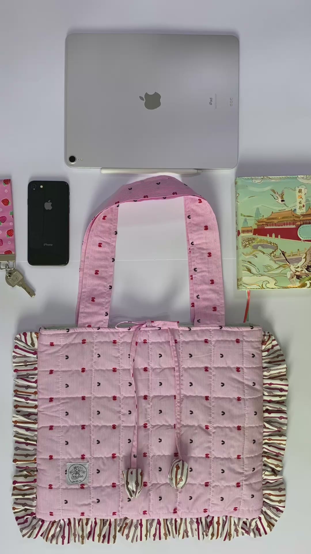 The video demonstrates that the tote bag can hold a 12.9-inch iPad along with a notebook, an iPhone, and other essentials.