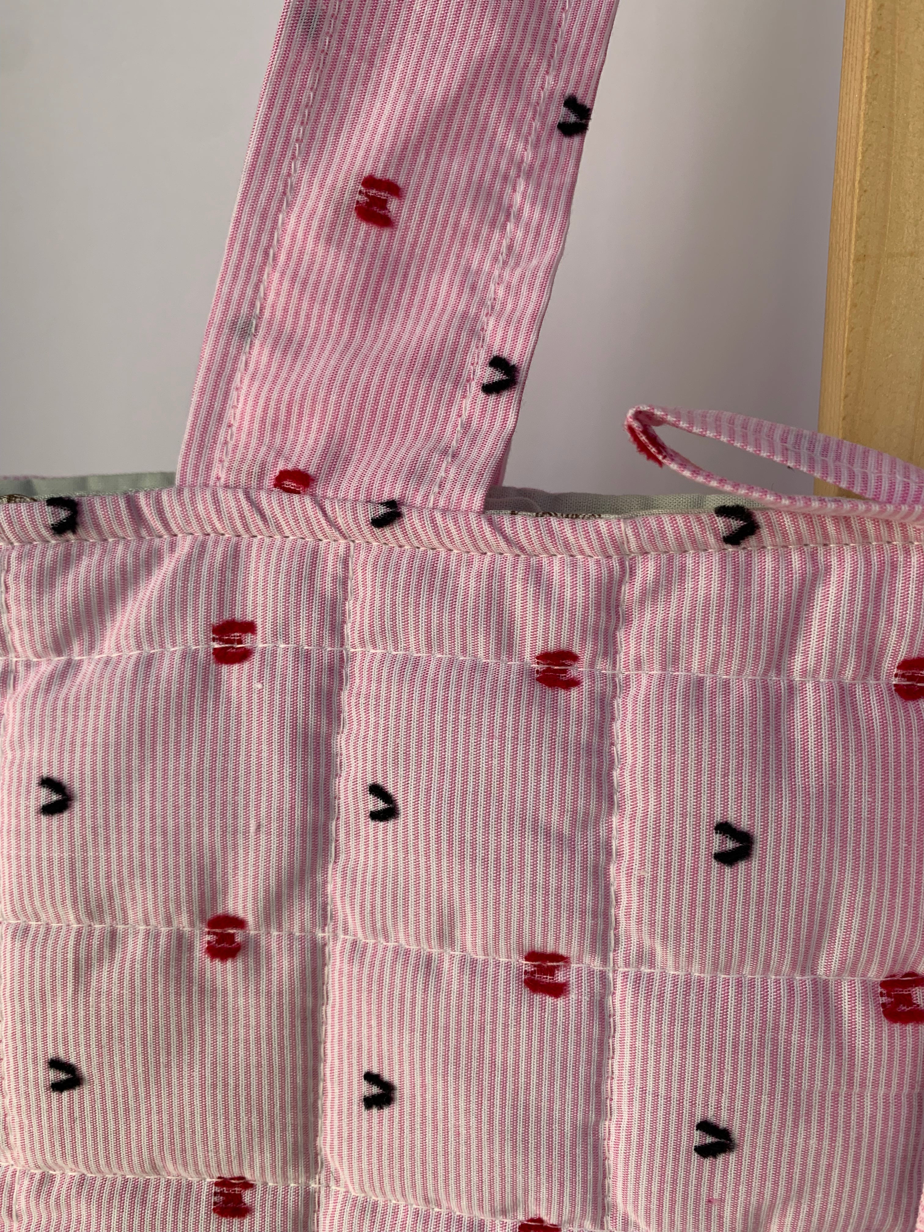 A close-up of a pink tote bag with a quilted pattern.