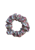 A fabric hair scrunchie with a pink and green floral pattern on a white background.